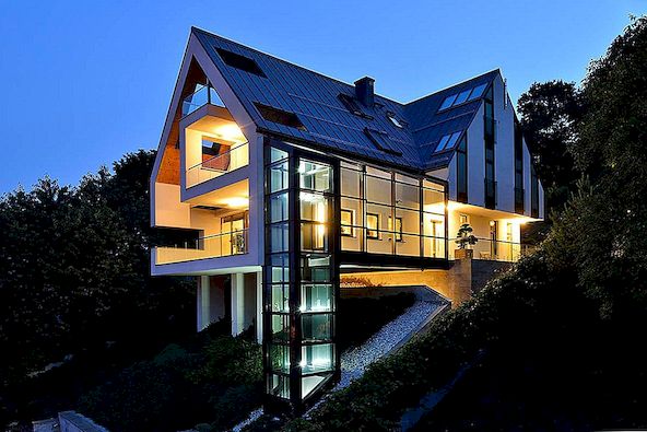 Ett hus på en sluttning ansluter sig till omgivningen genom en glashiss