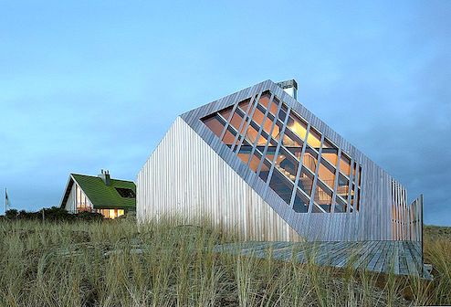 Modern strandhuis gevormd door de wind en het landschap